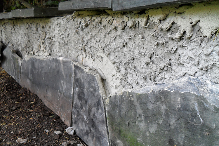 Lange gemauerte Sitzbank - Die Naturstein-Verkleidung mit Polygonalplatten ist stark beschdigt